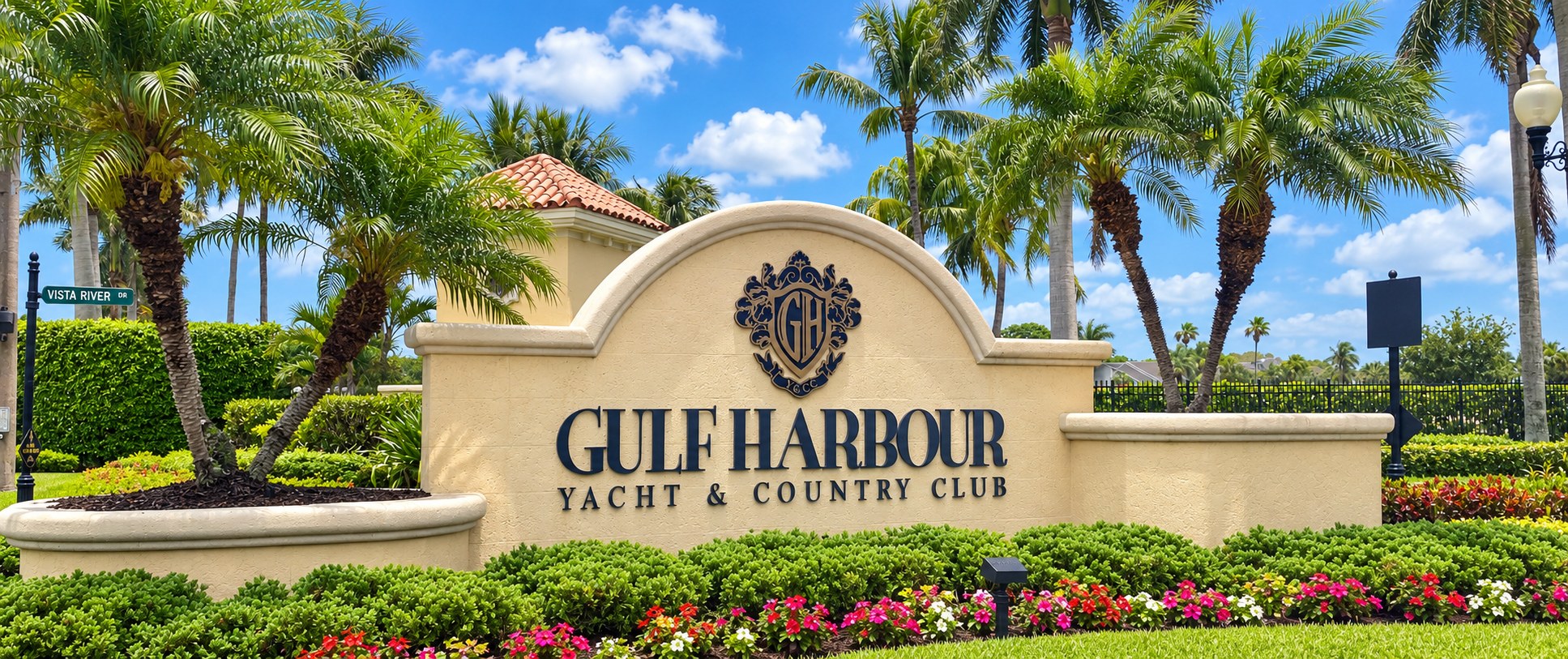 The Gulf Harbour Yacht and Country Club entrance sign in Fort Myers, with royal palms and flowering beds around it