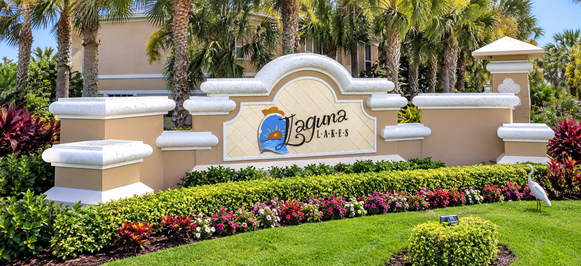 The Laguna Lakes entrance sign in Fort Myers, with flower beds, clipped hedging and palms